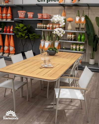 Salon de jardin avec table extensible en bois clair et fauteuils en aluminium gris et toile blanche dans un magasin.